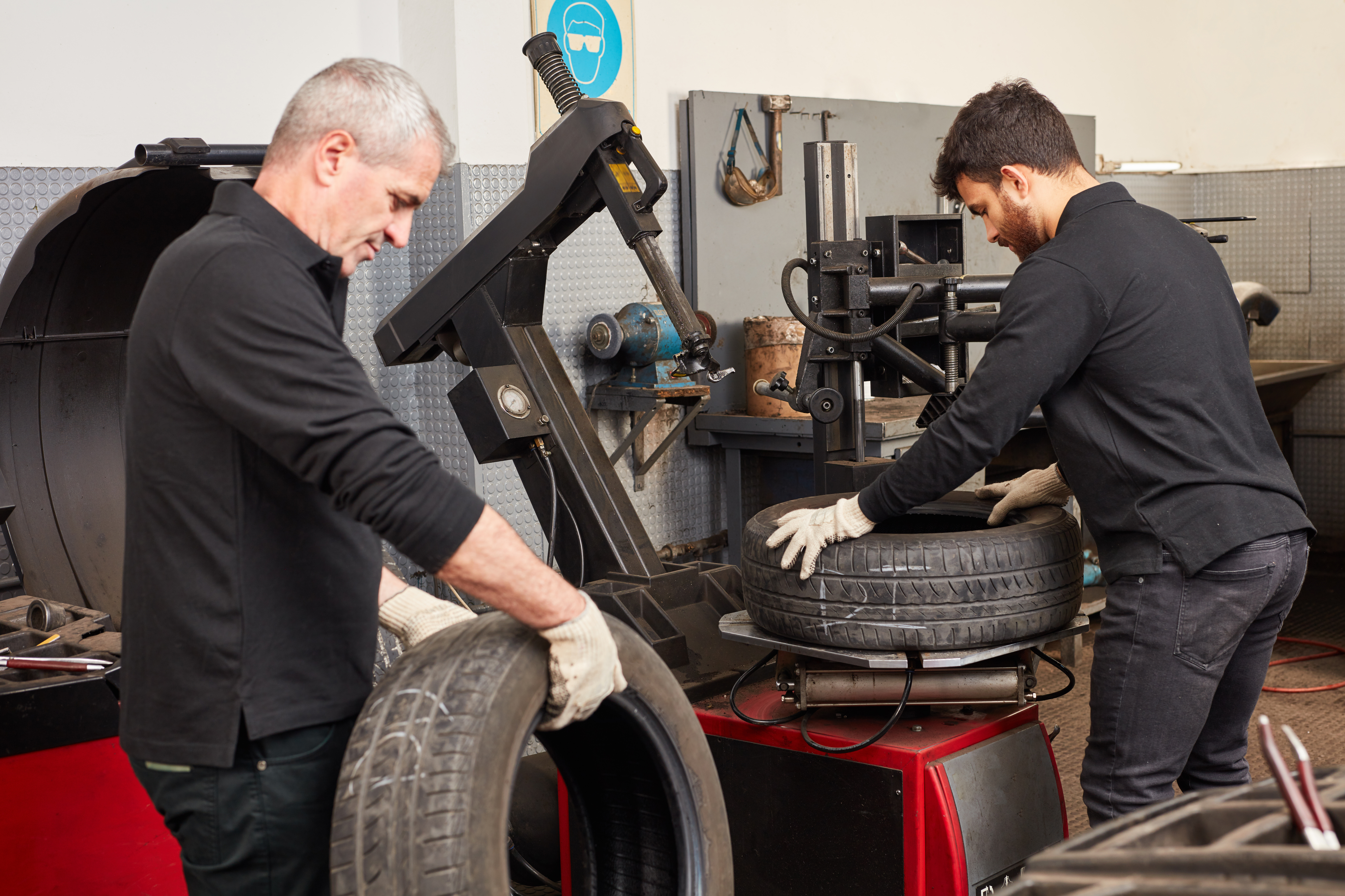 Zwei Mechatroniker in der Autowerkstatt mit Reifen