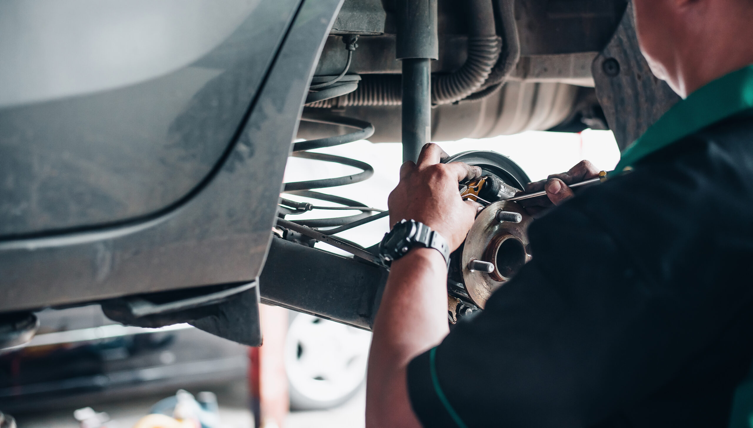Close-up of a mechanic’s hands repairing car brakes in a garage, focusing on vehicle maintenance and safety.